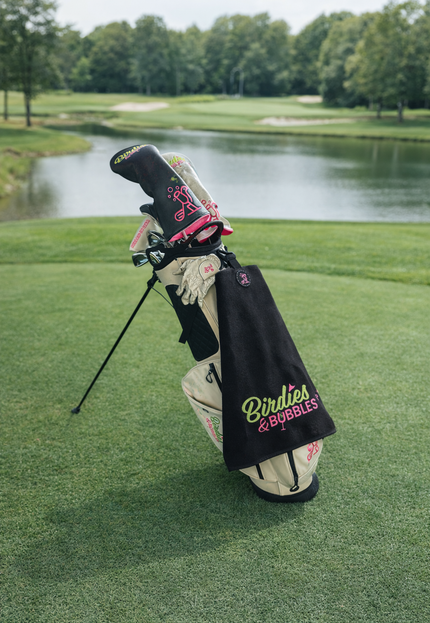 Magnetic golf towel with Birdies & Bubbles logo attached to golf bag
