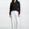 Woman wearing a black sweater with a logo and white pants on a white background